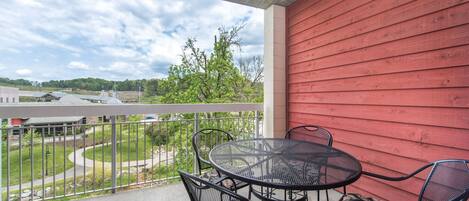 A balcony with a red wall, a round metal table, and two chairs with floral cushions.