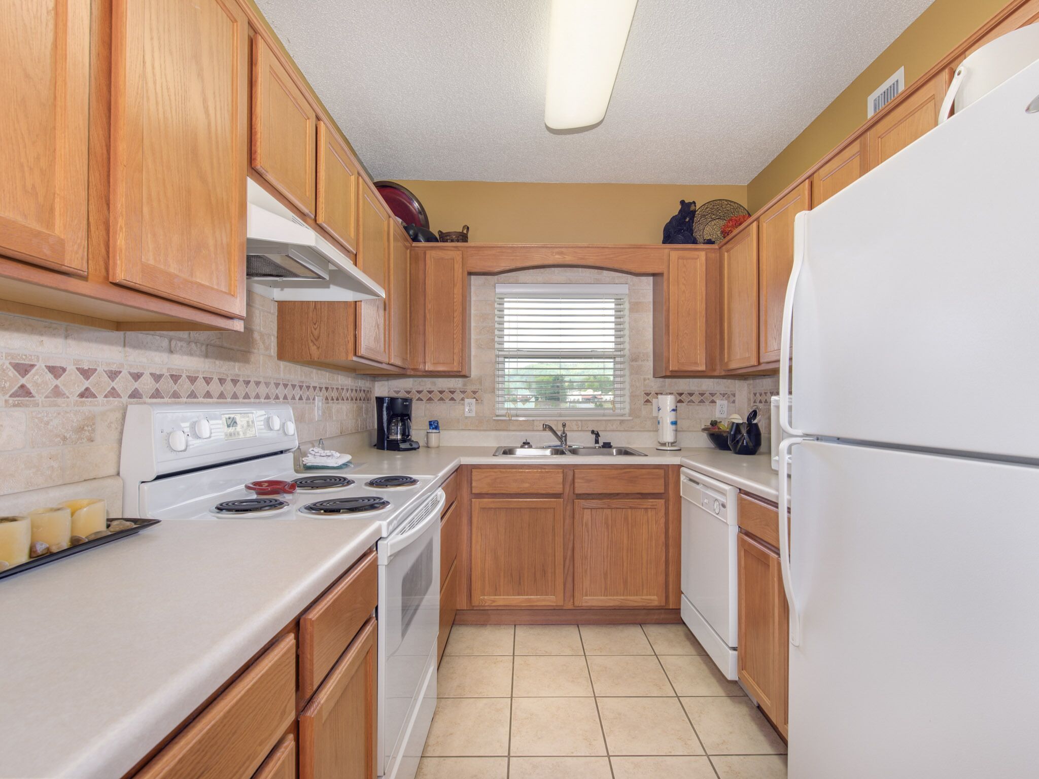 Una cocina compacta con armarios de madera, una estufa blanca, un lavabo y un refrigerador.