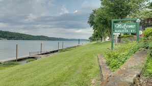 Placa verde dando as boas-vindas aos visitantes a Augusta, Kentucky, perto de um lago com área gramada e um píer.