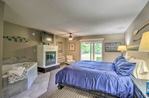 Une chambre dotée d’un grand lit, d’une baignoire, d’une cheminée et d’une fenêtre donnant sur un paysage verdoyant.