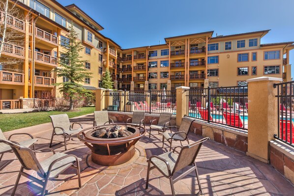 A courtyard with a fire pit, outdoor seating, and a pool area.