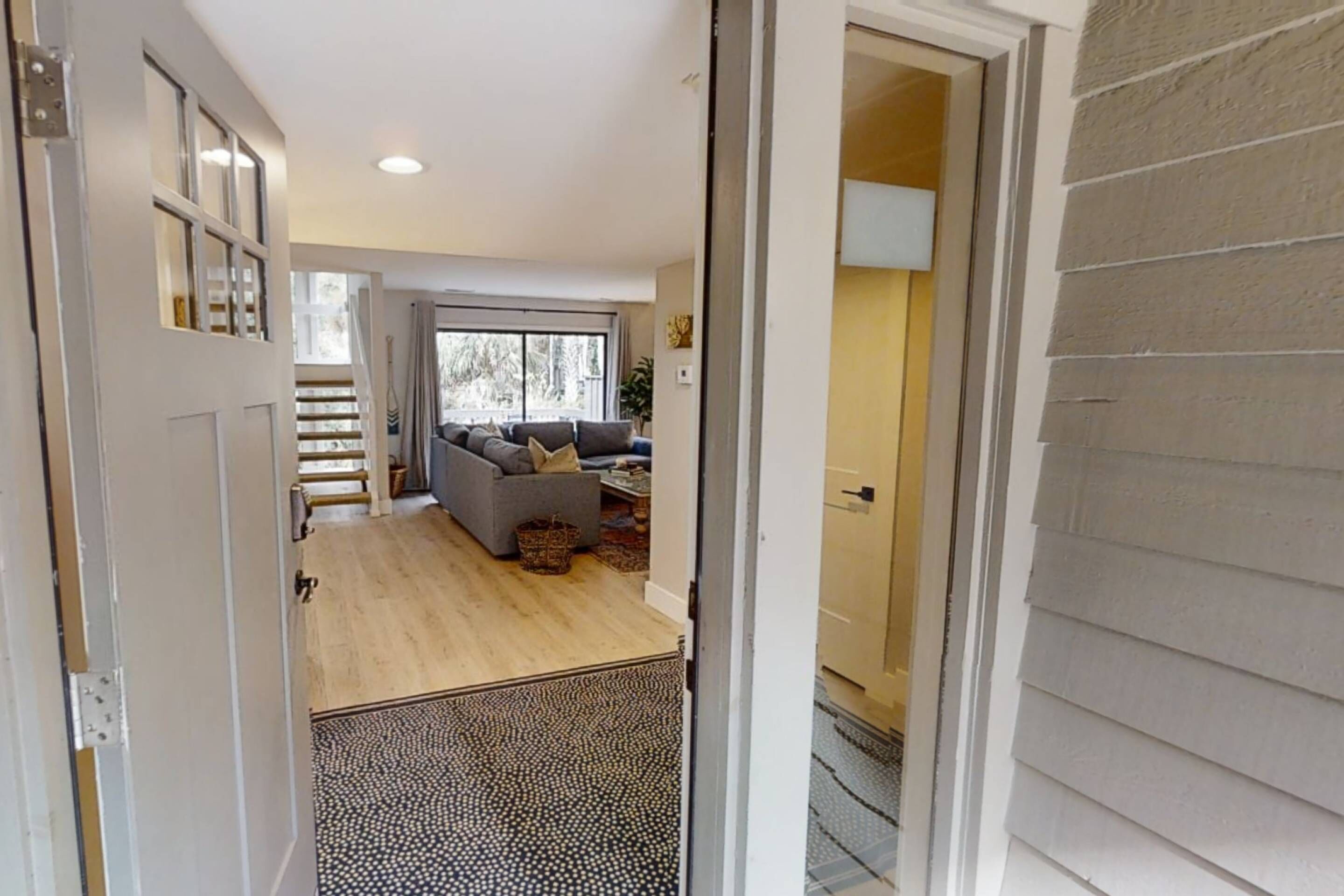 Un intérieur moderne avec un plancher en bois, un canapé gris et un escalier menant à un niveau supérieur.