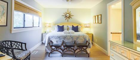 A bedroom with a bed, bedside tables, a chair, a dresser, and a large mirror.