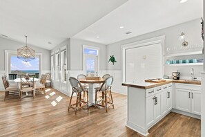 A modern kitchen with white cabinetry, a wooden island, and a view to the outside.