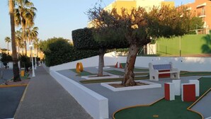 Zona ajardinada con un árbol, bancos y césped.