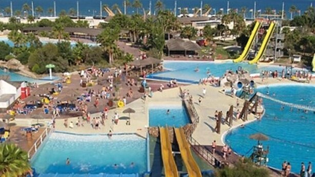 Un parque acuático con múltiples piscinas, toboganes y una zona de playa.