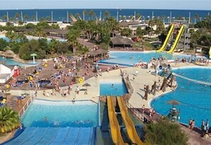 A water park with multiple swimming pools, slides, and a beach area.