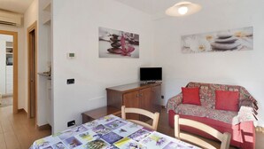 Quarto com cama, escrivaninha, televisão e sofá.