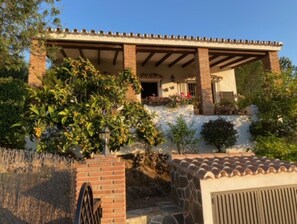 Ein Haus mit überdachter Terrasse, Ziegelmauern und einem Steinweg, der zum Eingang führt.