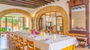 Zona de menjador amb una taula llarga preparada per a dinar, cadires de fusta i un mirall gran.