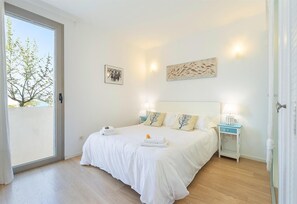 Une chambre à coucher avec un lit, des tables de chevet, une fenêtre et des œuvres d’art accrochées aux murs.