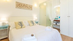 Habitación de hotel con cama, mesitas de noche, un espejo, armario y una obra de arte en la pared.