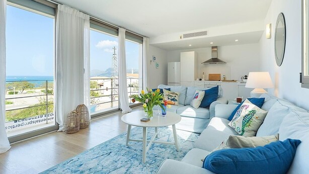Una sala de estar moderna con un sofá, una mesa de centro y vistas al mar.