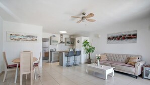 Un soggiorno moderno con zona pranzo, divano, tavolino e ventilatore a soffitto.