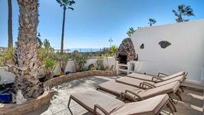 Una terrazza sul tetto con poltrona relax, un forno in pietra e vista sull'oceano.