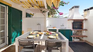 An outdoor dining area with a table set for a meal, a brick oven, and a green door.