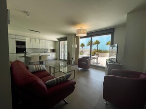 Een moderne woonkamer met een bank, een glazen salontafel en uitzicht op het balkon.