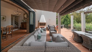 Ein möblierter Patio-Bereich im Freien mit Korbmöbeln, einem Kamin und einem überdachten Teil.