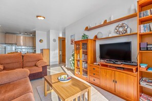 A living room with a sofa, TV, wooden cabinet, and a dining table. - Apartment in Bolnuevo with Sea View, Shared Pool, A/C & Wi-Fi (Bolnuevo)