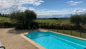 Ein Pool mit Blick auf Weinberge und einen klaren Himmel.