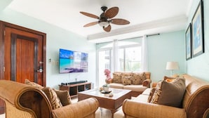 Un soggiorno con ventilatore a soffitto, televisore, divano e tavolino.