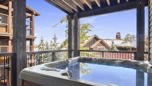 Un bain à remous situé dans un espace extérieur abrité, avec des poutres en bois et une vue sur les maisons voisines.