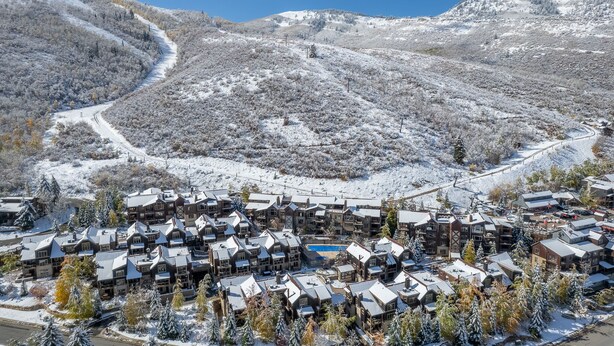 Une station de ski comprenant plusieurs bâtiments de style chalet, un télésiège et un paysage montagneux en toile de fond.