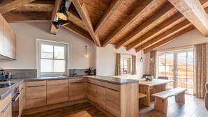 Eine moderne Küche mit Holzschränken, einer zentralen Kochinsel und einem Essbereich mit Bänken.