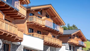 Eine mehrstöckige Holzhütte mit Balkonen, auf einem Steinfundament, unter blauem Himmel.