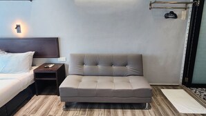 Une chambre à coucher moderne, comprenant un lit, un canapé, une table de chevet et un luminaire fixé au mur.