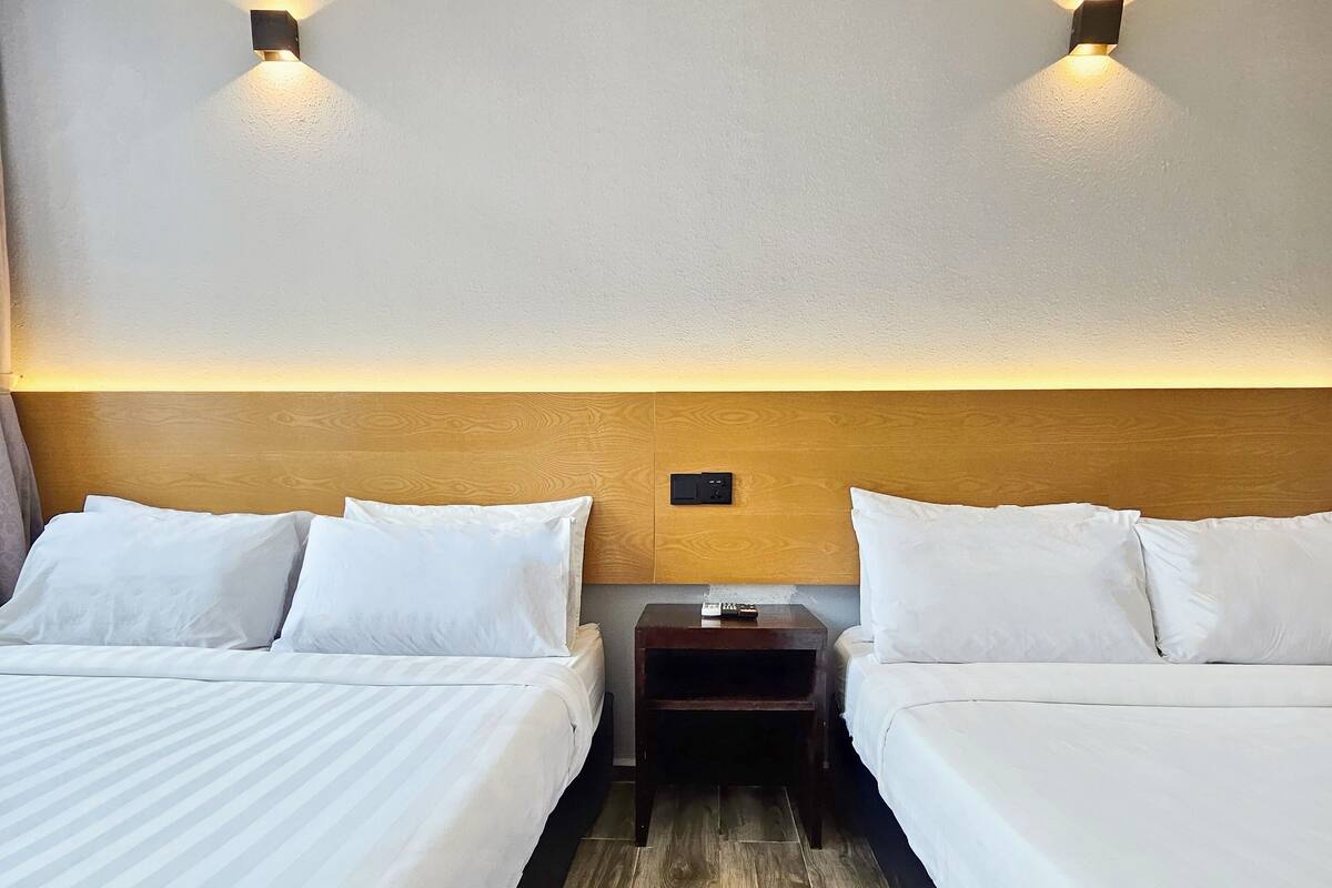 Ein Hotelzimmer mit zwei Betten, einem Holzkopfteil und zwei Wandleuchten.