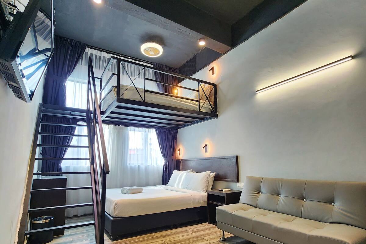Ein modernes Hotelzimmer mit einem Etagenbett, einer Schlafcouch und einer Treppe.