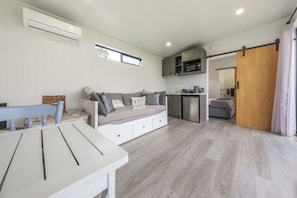 Un intérieur moderne comprenant un canapé, une table à manger, un coin cuisine et une porte coulissante.