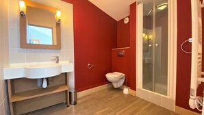 Une salle de bain avec un lavabo blanc, des toilettes et une douche à parois de verre.