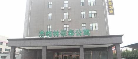Un edificio moderno con un letrero que dice "格林豪泰公寓" (Green Lin Ha Tai Apartments).