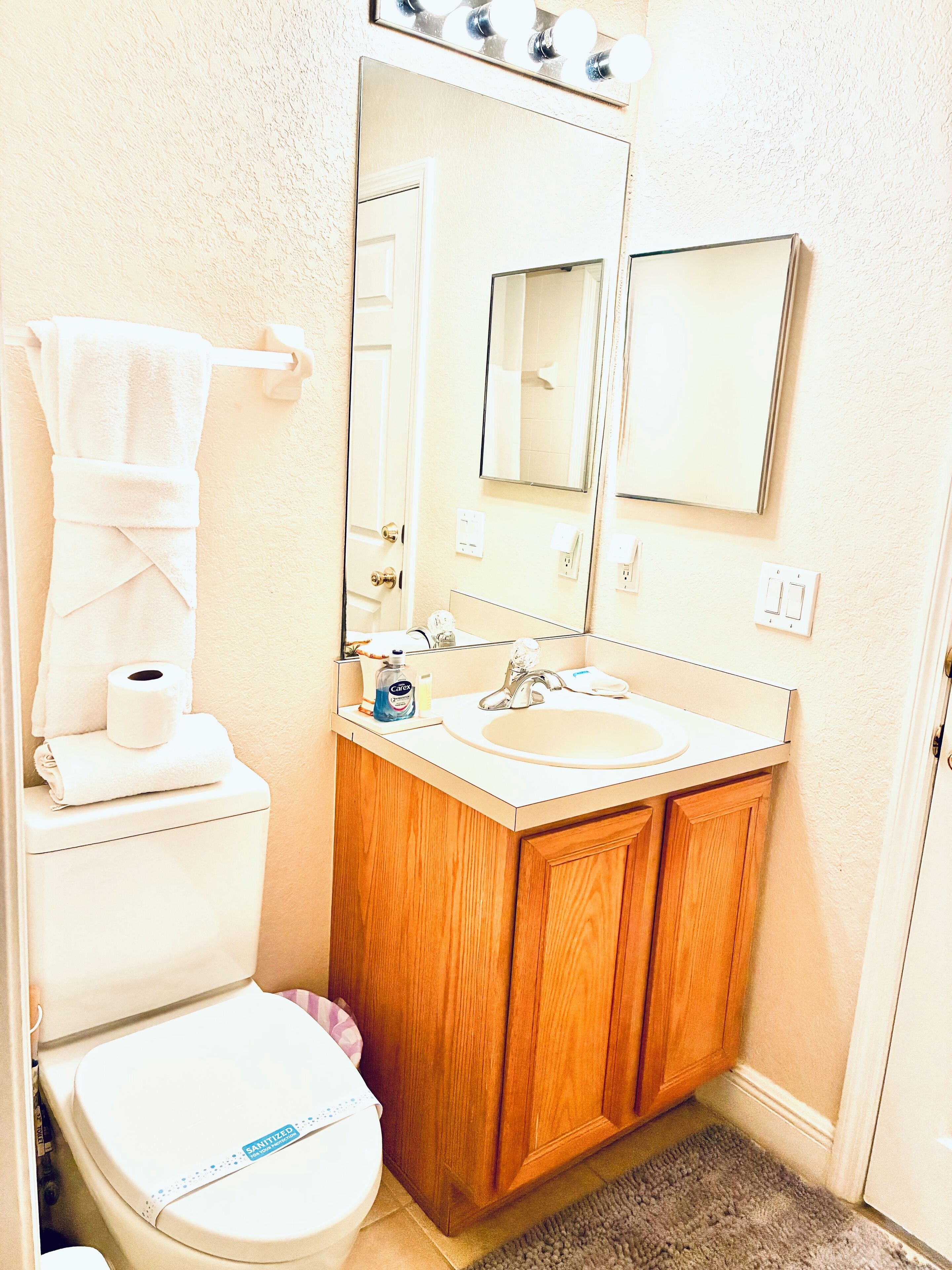 Een badkamer met toilet, wastafel en spiegel.