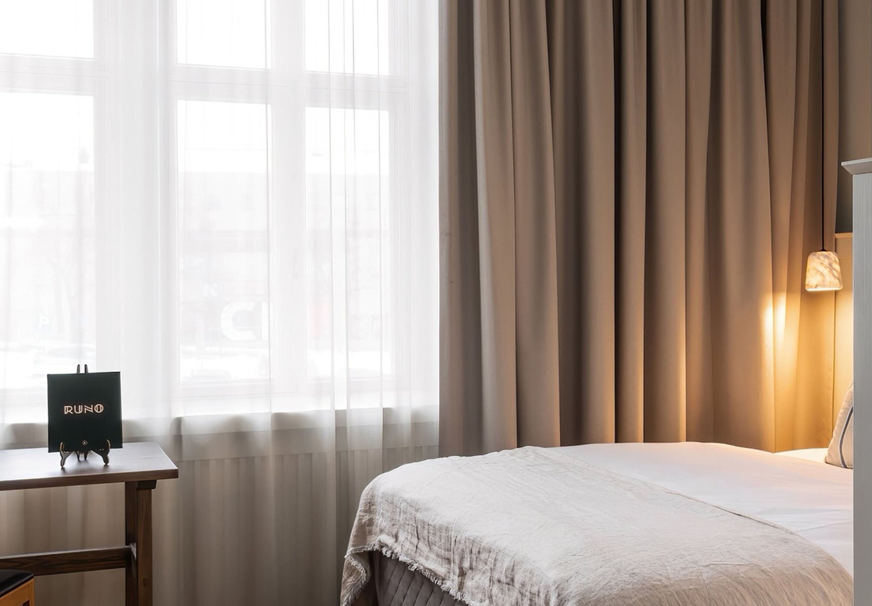 A hotel room with a bed, a table with a 'RUN' sign, and a lamp.