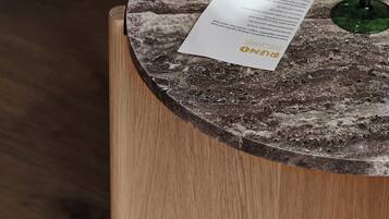 A round wooden table with a marble-like top, two green wine glasses, and a menu.
