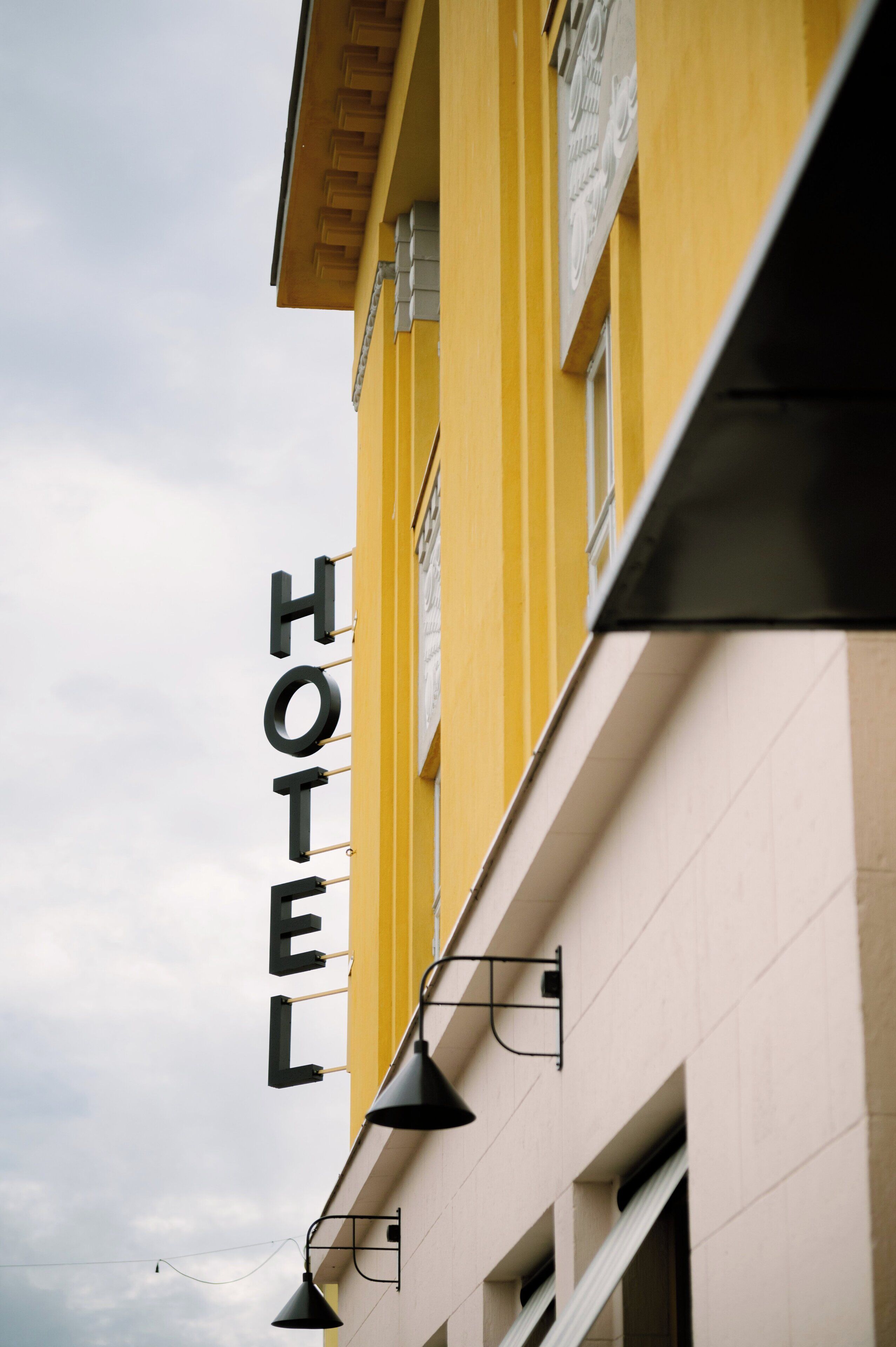 Segnaletica di un hotel con la scritta 'HOTEL' a caratteri grandi su un edificio giallo.