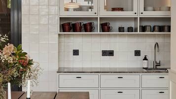 Uma cozinha moderna com armários brancos, uma mesa de jantar de madeira e iluminação pendente.