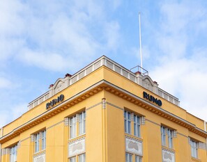 A building with the name 'RUNO' on its facade, featuring a yellow exterior and decorative window frames.