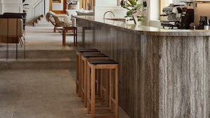 A modern kitchen with a central island, bar stools, a coffee machine, and a view of the dining area. - RUNO Hotel Porvoo (Porvoo)