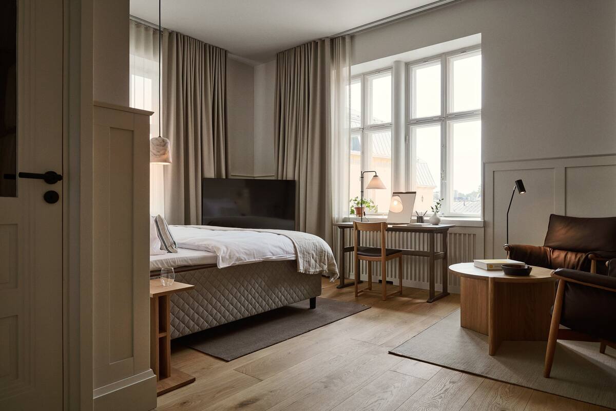 A bedroom with a bed, a desk, a chair, and a TV.