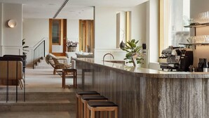 A modern kitchen with a marble island, wooden stools, and a coffee machine. - RUNO Hotel Porvoo (Porvoo)