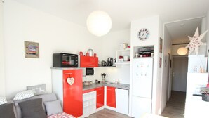 A compact living space with a kitchenette, a sofa with patterned cushions, and a dining table.
