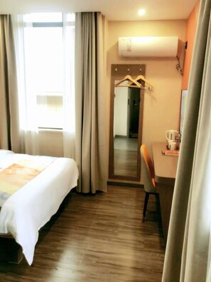 A hotel room with a bed, a desk, a chair, a mirror, and a wardrobe. - Shell Shanghai Jinshan Wanda Plaza Hotel (Shanghai)