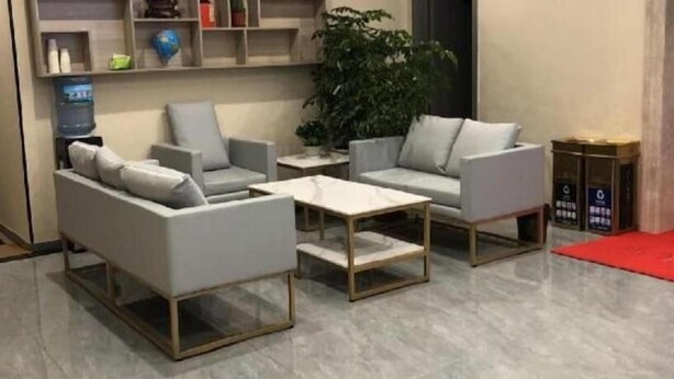 A modern living room with two grey sofas, a coffee table, and a side table. There is a large potted plant and a water dispenser on a shelf. - Shell Shanghai Jinshan Wanda Plaza Hotel (Shanghai)