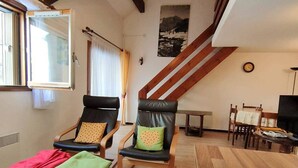 A living room with two leather chairs, a wooden table, a staircase, and a dining area. - 2-Bedroom Apartment with Parking, Sleeps 4/6 (Cauterets)