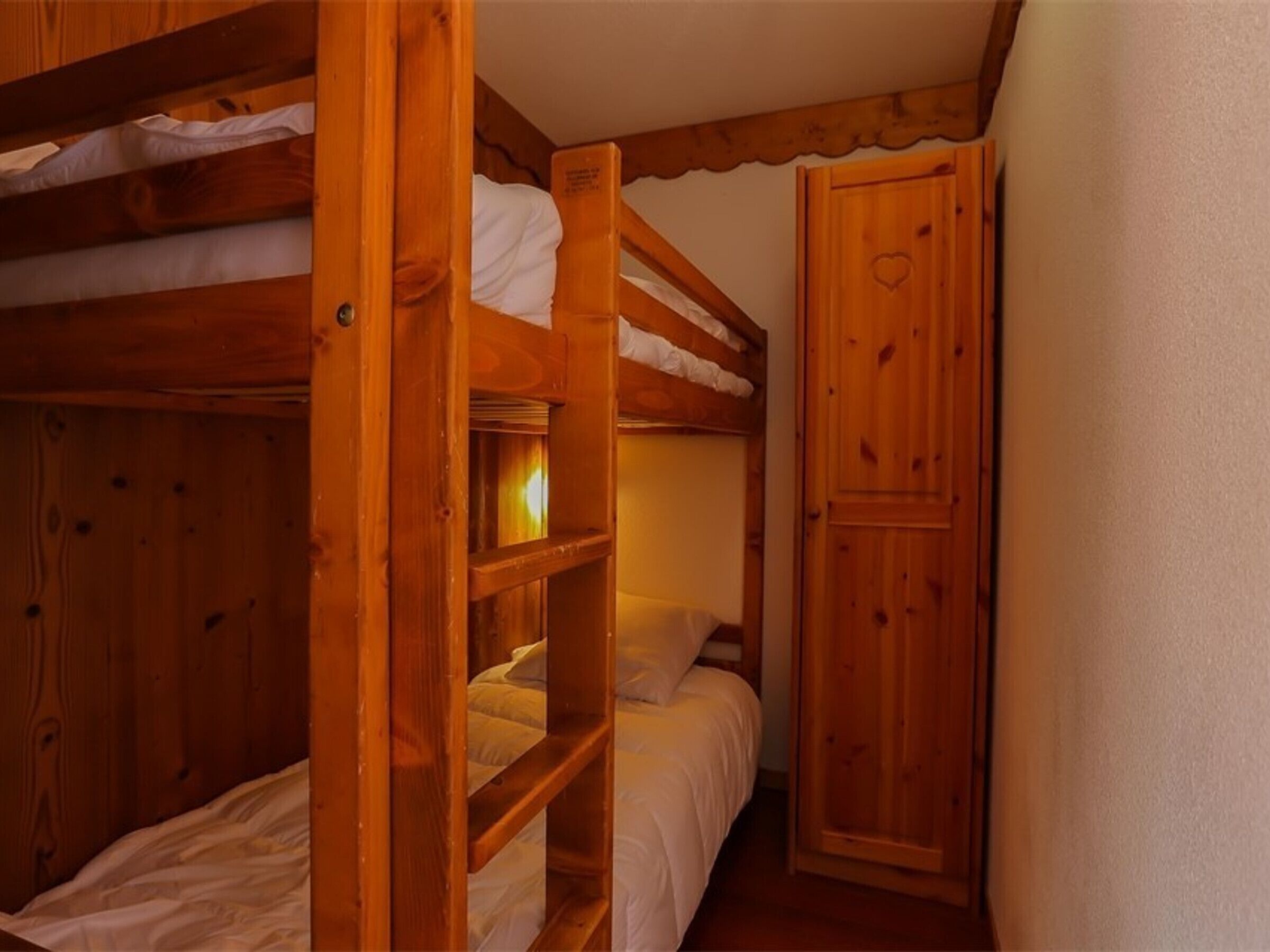 Camera con un letto a castello in legno, un letto singolo e un armadio.