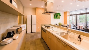 Una cucina moderna con forno integrato, microonde ed elettrodomestici. Un'ampia finestra offre luce naturale e vista sull'esterno.